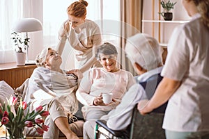 Young caregiver comforting elderly woman in nursing home