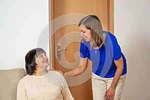 Young caregiver helping senior woman at home. Caring nurse assisting her middle aged female patient.