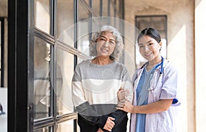 Young caregiver helping senior woman walking. Nurse assisting her old woman patient at nursing home. Senior woman with