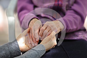 Young caregiver holding seniors hand. Elderly concept