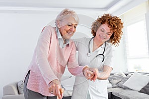 Young carer supporting senior disabled woman with walking stick. Portrait of happy female caregiver and senior woman walking