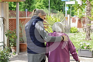 Young carer walking with the elderly woman in the garden