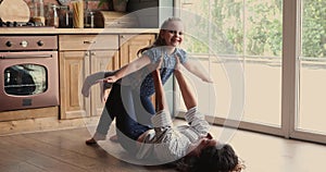 Young caring mother playing airplane with cute daughter.