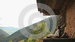 Young carpathian countryman sitting on the brink of mountain shelter in Carpathians