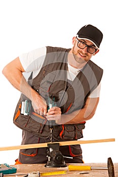 Young carpenter drilling a hole in a wooden slat isolated over w