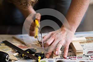 Young carpenter, handyman working with wood, cutting with handsaw