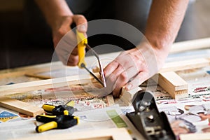 Young carpenter, handyman working with wood, cutting with handsaw