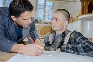 Young carpenter trainee learning with mentor