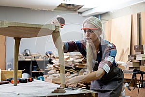 young carpenter women using measuring tape looking wood size at workspace. craftsman profession in wood factory