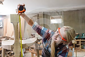 young carpenter women using measuring tape looking wood size at workspace. craftsman profession in wood factory. professional