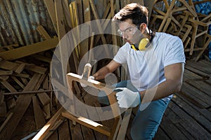 Young carpenter or woodworker with safety glasses, ear muff and protective gloves is sanding wood with Brass Wire Brush Wood photo