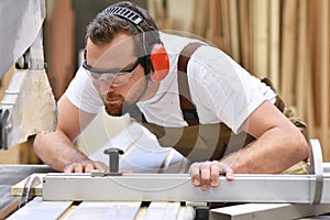 Young carpenter in working clothes works in the joinery on a san