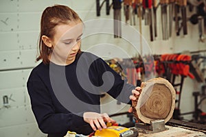 Young carpenter working with wood and sandpaper in craft workshop. School, development and learning concept