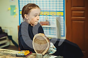 Young carpenter working with wood and sandpaper in craft workshop. School, development and learning concept