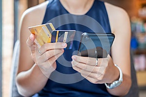 Young casual Business woman holding credit card and using touchscreen smartphone for online shopping while making orders in the