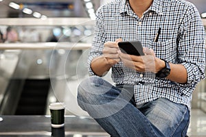 Young casual Businessman Sitting and using smartphone between drinking hot coffee. business, lifestyle, technology and Social