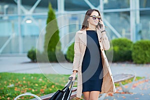 Young casual female goes at airport at window with suitcase waiting for plane