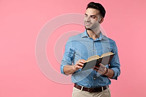 Young casual guy holding book and looking to side