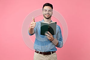 Young casual guy holding book and making thumbs up sign