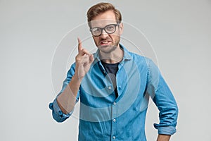 Young casual guy pointing finger up and contesting