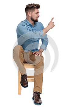 Young casual man in denim shirt showing finger and warning