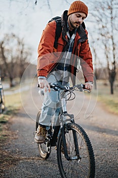 Young casual man enjoying a peaceful ride on his bicycle in the park