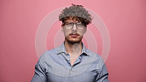 Young casual man with glasses on pink background