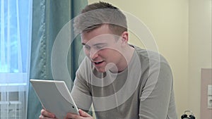 Young casual man have a video call via tablet at home