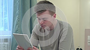 Young casual man have a video call via tablet at home