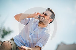 Young casual man holding mobile phone and credit card outdoor