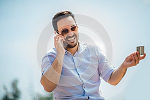 Young casual man holding mobile phone and credit card outdoor