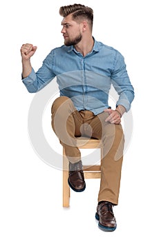 Young casual man looking to side and holding fist up