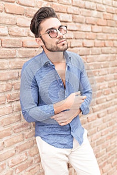 Young casual man near brick wall looking up