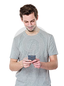 Young casual man reading something on his phone and smiling