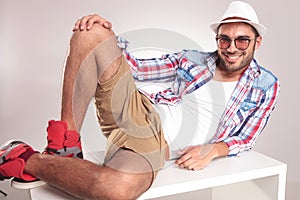 Young casual man resting on a white table