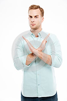 Young casual man showing stop gesture with arms crossed