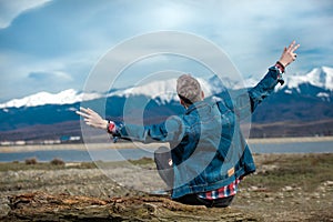 Young casual man sits on  wood log and celebrates freedom