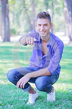Crouched man pointing at you in park photo
