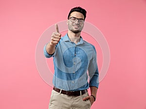 Young casual man smiling and making thumbs up sign