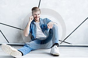 Young casual man talking on the phone while lying on the floor.