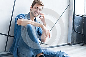 Young casual man talking on the phone while lying on the floor.