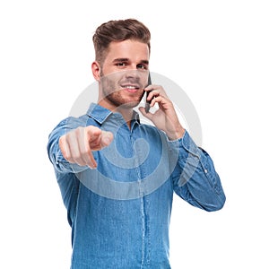 Young casual man talking on the phone points finger