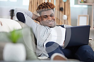 young casual man using pc on sofa photo