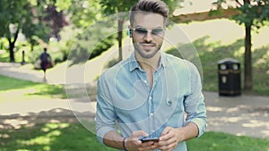 Young casual man walking and texting on smart phone