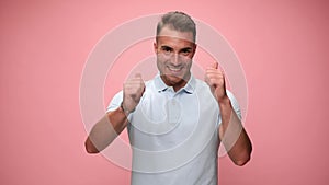 Young casual man wearing polo shirt on pink background