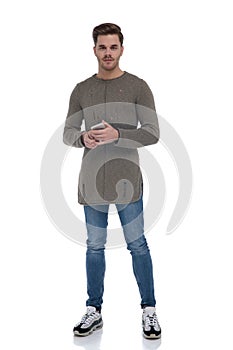 Young casual man wearing sweater and holding phone