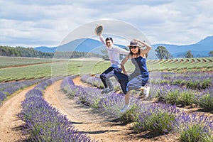 Young casual trendy boy and girl jumping at lavender field. Blue cloud summer daytime.