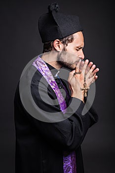 Young catholic priest praying