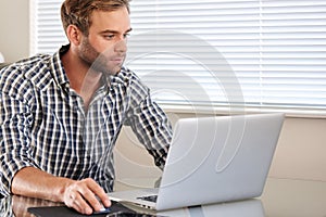 Young caucasian adult man busy using a laptop and mouse