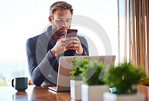 Young caucasian adult man messaging on his phone at home